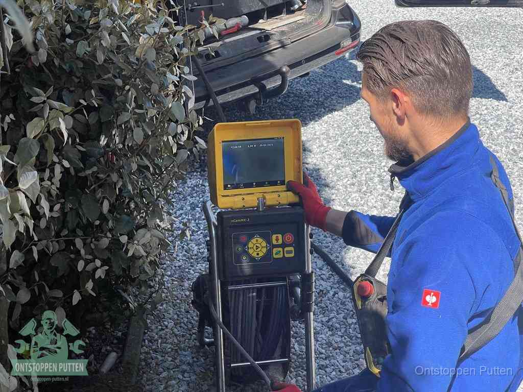 Monteur bedient een rioolinspectiecamera met monitor voor rioolinspectie in Putten