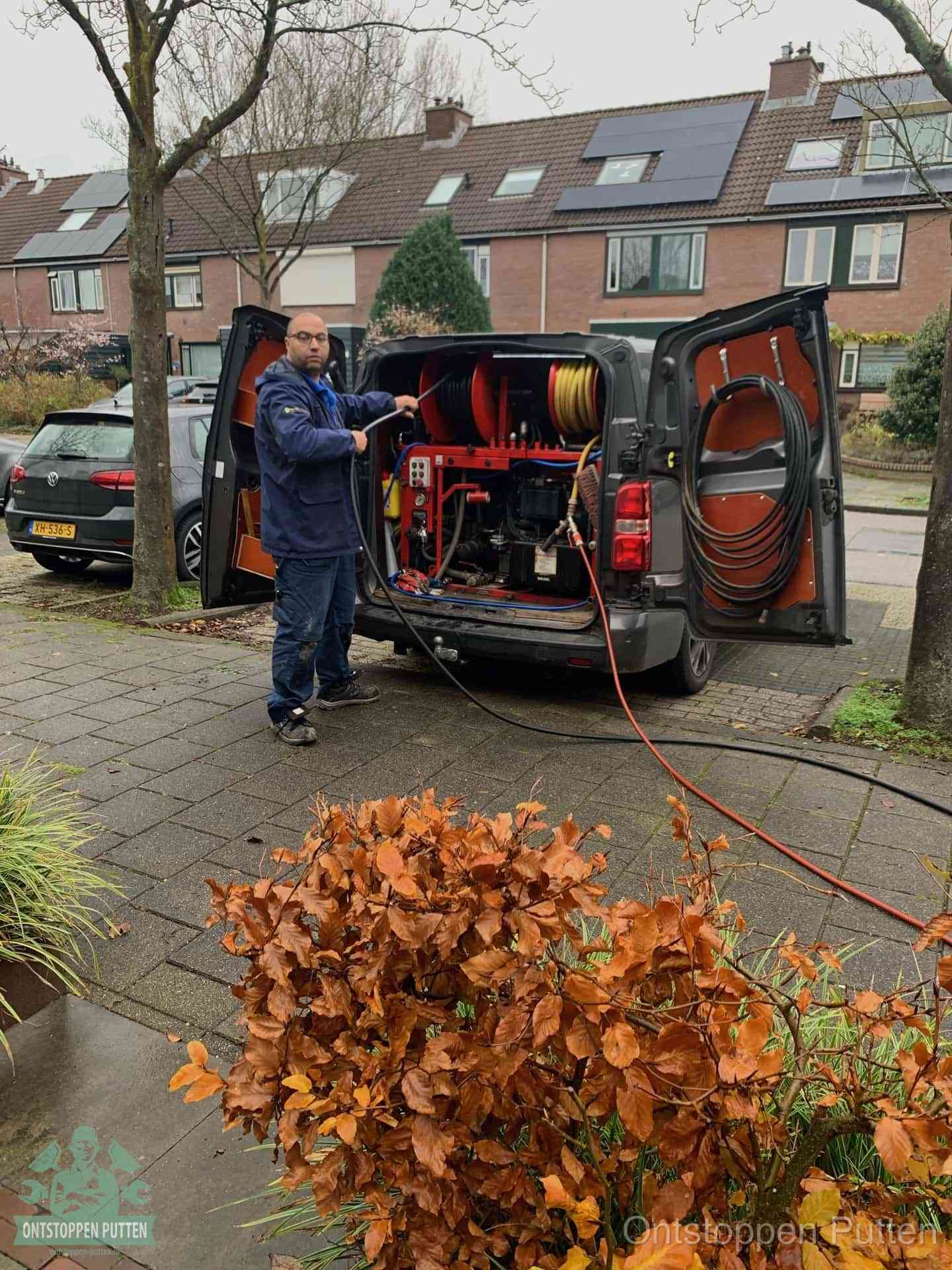 Monteur met rioolreinigingsbus levert rioolservice in de wijk in Putten