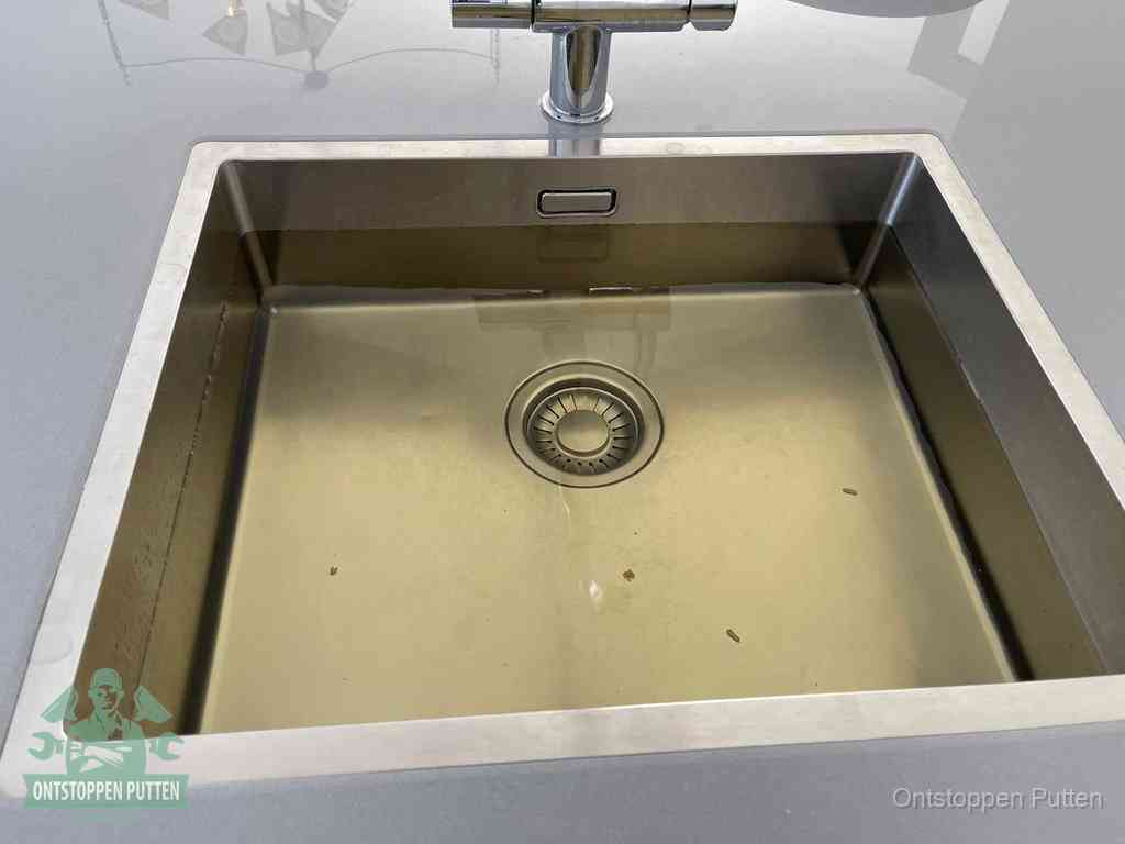 Stilstaand water in een rvs spoelbak dat niet wegloopt, een duidelijk signaal van een gootsteenverstopping in Putten