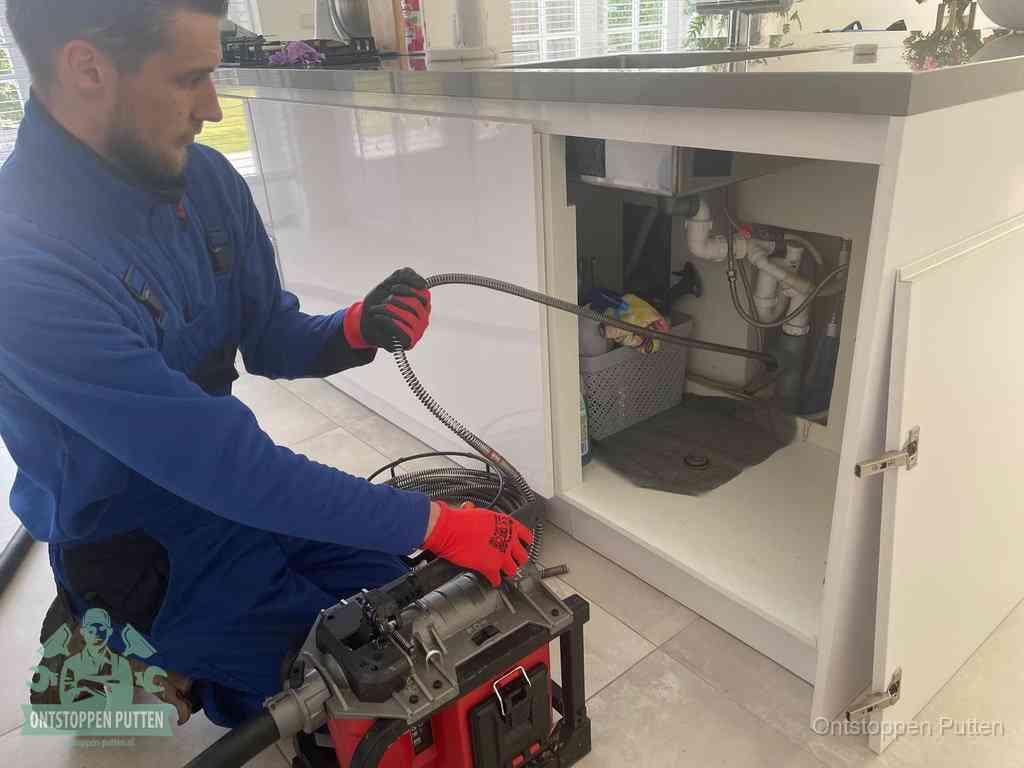 Een monteur reinigt de keukenafvoer grondig met een veermachine om terugkerende gootsteenverstoppingen te voorkomen in Putten
