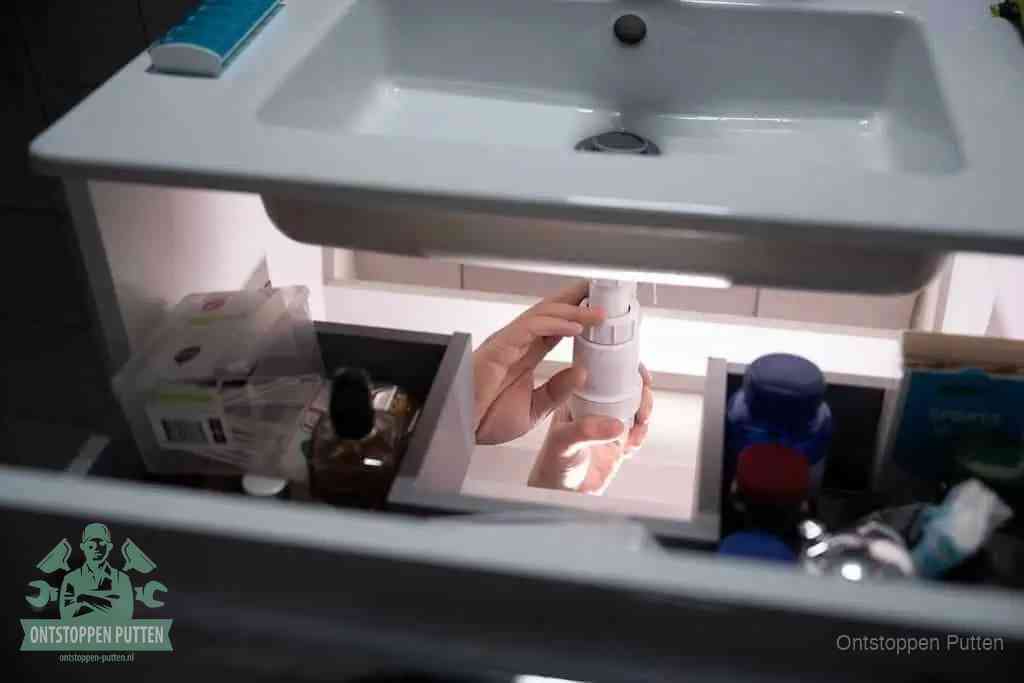 Een pompfles met zeep boven een wastafel in de toiletruimte, de warm water en afwasmiddel-methode om de wc te ontstoppen in Putten