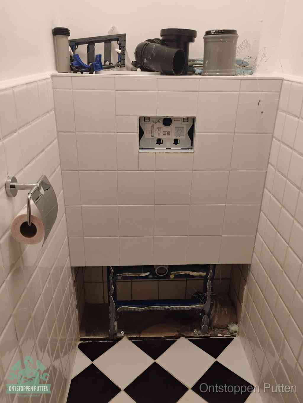 Een toiletruimte waar het hangtoilet en de inbouwreservoir-onderdelen zijn vrijgelegd voor onderhoud, periodiek nazicht voorkomt een wc-verstopping in Putten